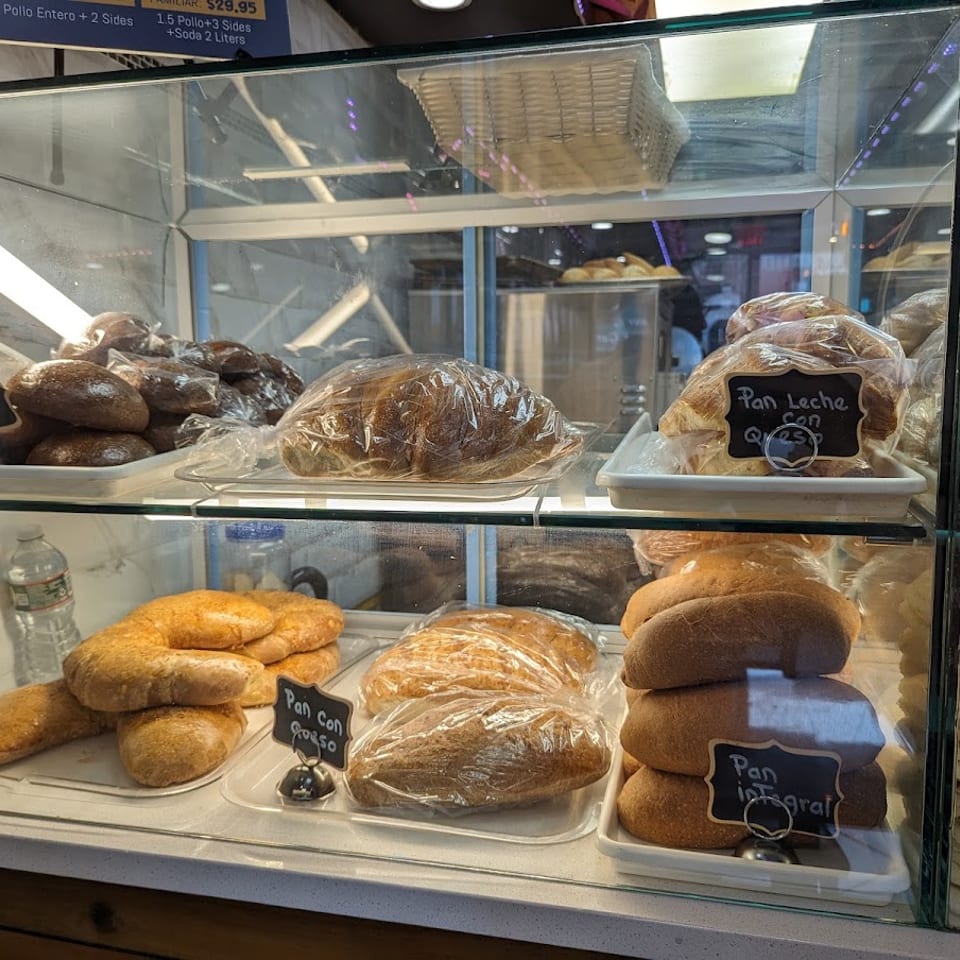 A glass display case filled with various types of bread and tortillas, some labeled with prices.